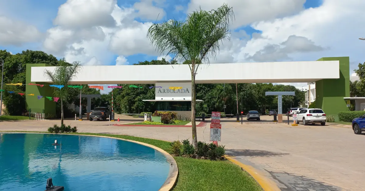 Entrada principal de Residencial Arbolada en Cancún, con caseta de seguridad y fuente